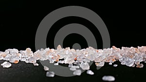 Falling salt crystals scattered on a wood table, showing the charm of Himalayan salt. Slow motion