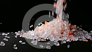 Falling salt crystals scattered on a wood table, showing the charm of Himalayan salt. Slow motion