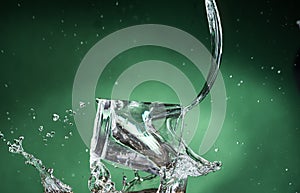 Falling small glasses and spilling water on a green background