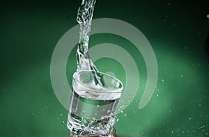 Falling small glasses and spilling water on a green background