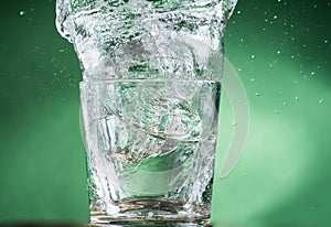 Falling small glasses and spilling water on a green background