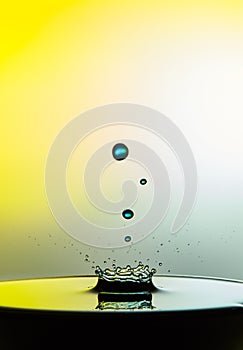 Falling water drop close up image with a yellow background