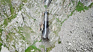 Falling waterfall breaks on the rocks. The circle of stones and herbs.