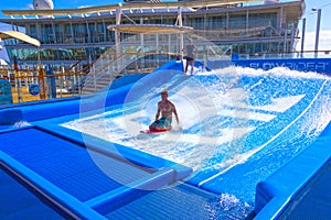 Falmouth, Jamaica - May 02, 2018: Woman surfing on the FlowRider aboard the Oasis of the Seas by Royal Caribbean