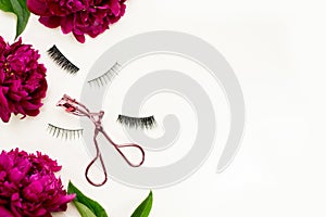 False eye lashes, pink curler and flowers red peony on white background. Beauty concept - Tools for eyelash extension