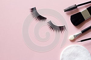 False eyelashes and cosmetic tools for eye makeup on pink background, concept