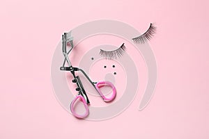 False eyelashes and curler on pink background