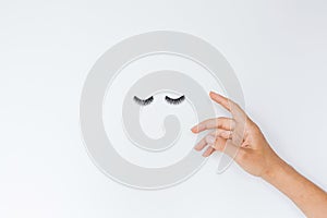 False Eyelashes and female hand Lying On White Background. Beauty And Makeup Concept. Flatlay, Mockup, Overhead, Top view