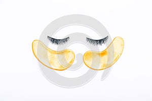 False eyelashes and golden patches on a white background. The view from the top.