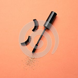 False eyelashes and mascara on orange background