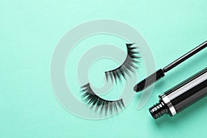 False eyelashes and mascara on turquoise background. Space for text