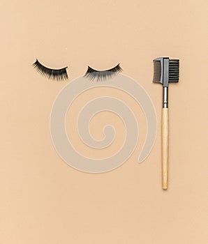 False eyelashes and a mini comb on a beige background