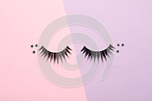 False eyelashes and sparkles on color background