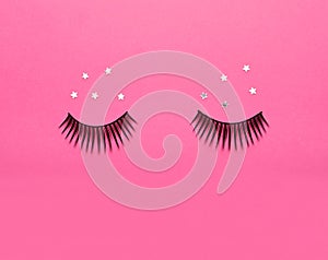 False eyelashes and sparkles on pink background