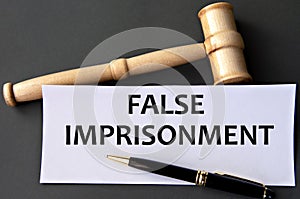 FALSE IMPRISONMENT - words on white paper on dark background with judge\'s gavel photo