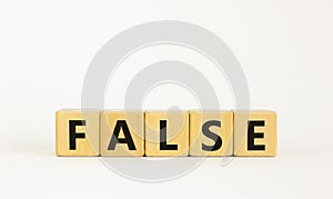 False symbol. The concept word `false` on wooden cubes. Beautiful white table, white background, copy space. Business, true or