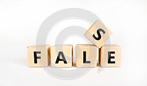 False symbol. The concept word `false` on wooden cubes. Beautiful white table, white background, copy space. Business, true or