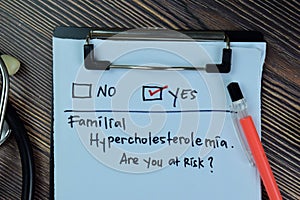 Familial Hypercholesterolemia, Are you at Risk? Yes write on a paperwork isolated on Wooden Table photo