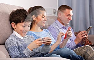 Family absorbedly looking at smartphones