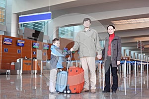 Family in airport hall with suitcases full bod