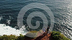 Family approach the edge of the cliff rock and look down, enjoying breathtaking