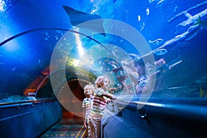 Family in aquarium. Kids watch fish, marine life