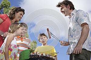 Family Around Grill In Garden