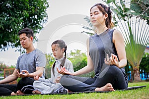 Family Asian parent and child daughter yoga poses together on a yoga mat at home garden. Family outdoors. Parent with child spends