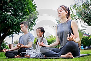 Family Asian parent and child daughter yoga poses together on a yoga mat at home garden. Family outdoors. Parent with child spends