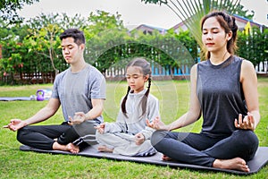 Family Asian parent and child daughter yoga poses together on a yoga mat at home garden. Family outdoors. Parent with child spends