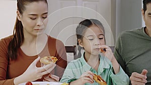 Family Asian people are happy to eat enjoy tasty pizza at home. Parents and daughter eating delicious Italian food from takeaway d