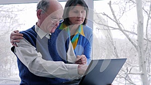 Family atmosphere, old people work with computer on Internet indoors