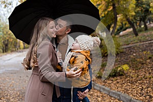 Family in autumn in forest rain umbrella