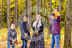 Family, autumn, happiness and people concept - mother, father, son and daughter playing in autumn park