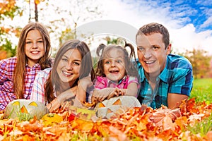 Family in autumn leaves with Halloween pumkins