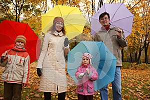 Family in autumn park with coloured umbrellas