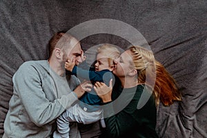 Family with baby in bed, kissing and hugging kid