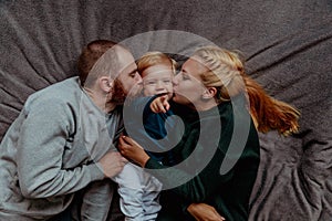 Family with baby in bed, kissing and hugging kid