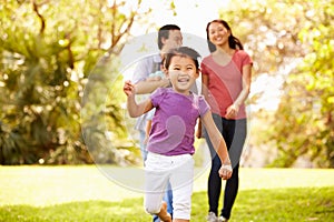 Family With Baby In Carrier Walking Through Park