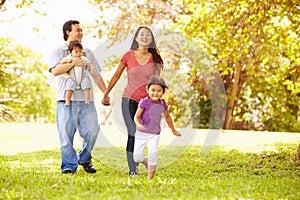 Family With Baby In Carrier Walking Through Park