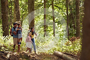 Family With Backpacks Hiking Or Walking Through Woodland Countryside