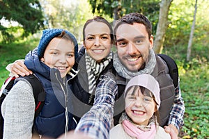 Family with backpacks taking selfie and hiking