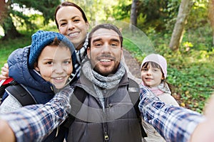 Family with backpacks taking selfie and hiking