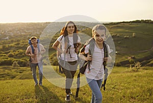 Family with backpacks on tourist trip in mountains. Cute girl with parents camping in wilderness during summer vacation