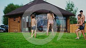 Family in the backyard of a country house in the summer relax playing with water and hosing