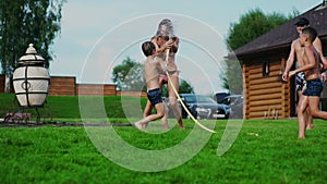 Family in the backyard of a country house in the summer relax playing with water and hosing