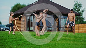 Family in the backyard of a country house in the summer relax playing with water and hosing