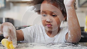 Family baking - black little girl playing with a flour on the table