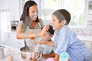 Family baking and mother teaching children to bake cake in the kitchen of their home. Happy latino kids and woman play
