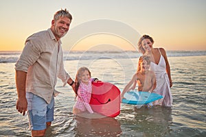 Family, beach and body board, kids with parents in water on summer holiday. Mom, dad and children surfing in ocean at